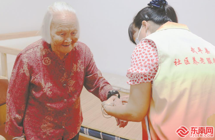 龙岩市武平县平川街道东城社区孝老员为老人戴上智能手环。福建日报记者 潘园园 摄