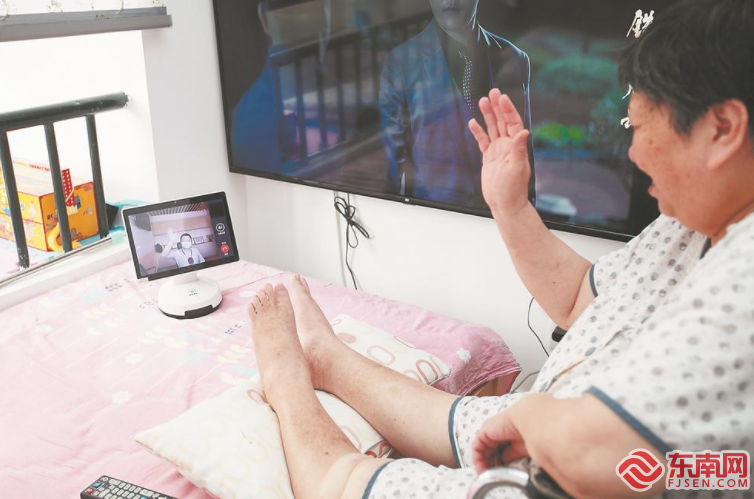在厦门市湖里区金山街道，一位下肢行动不便的独居老人在家中使用智能可视“机器人”与街道养老服务照料中心的工作人员进行通话。福建日报记者 施辰静 摄
