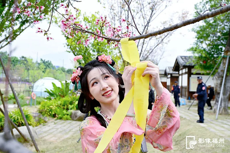 花朝节活动中“赏红护花”环节将彩带系在枝头。记者 石美祥 摄