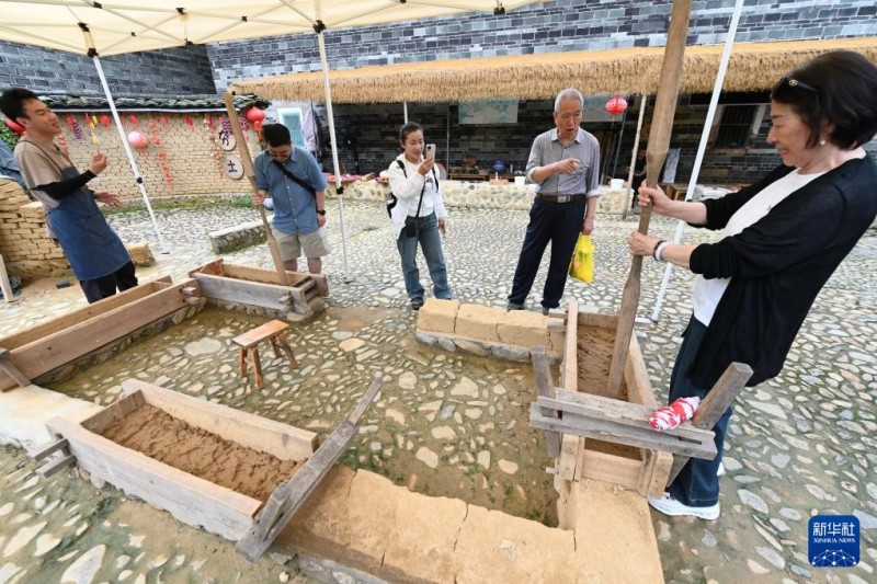 4月9日，游客在福建土楼（南靖）景区的土楼之光文化园体验客家土楼营造技艺。新华社记者 林善传 摄