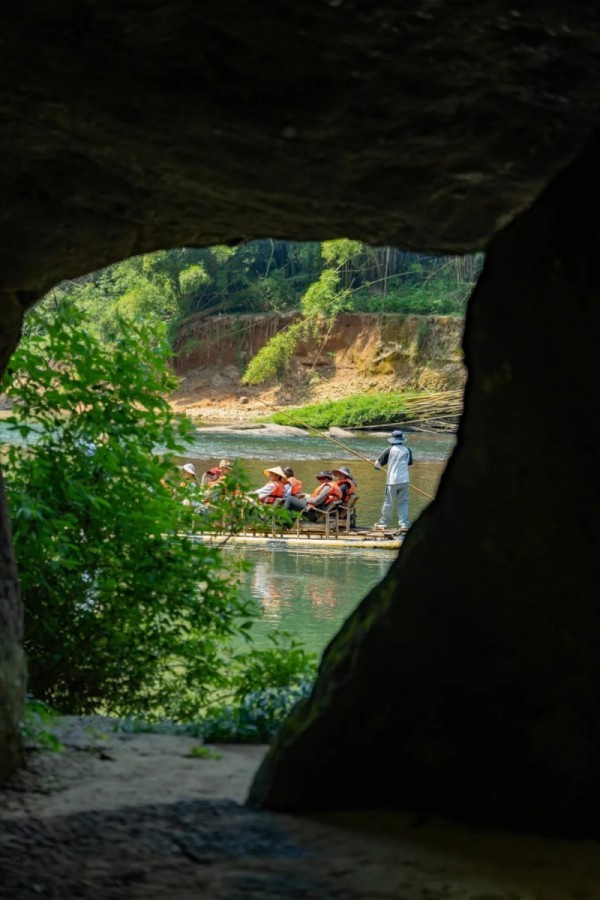 游客坐在竹筏上远眺群山、观赏水景，在流动的山水间感受春日出游的美好。