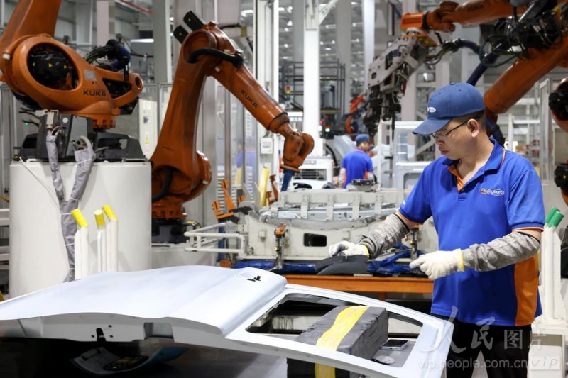 4月16日，在福州荻原泰山友模具冲压有限公司生产车间内，工人配合机器人在生产汽车车身钣金件产品。