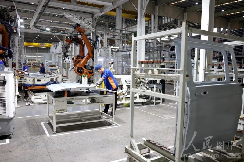 4月16日，在福州荻原泰山友模具冲压有限公司生产车间内，工人配合机器人在生产汽车车身钣金件产品。