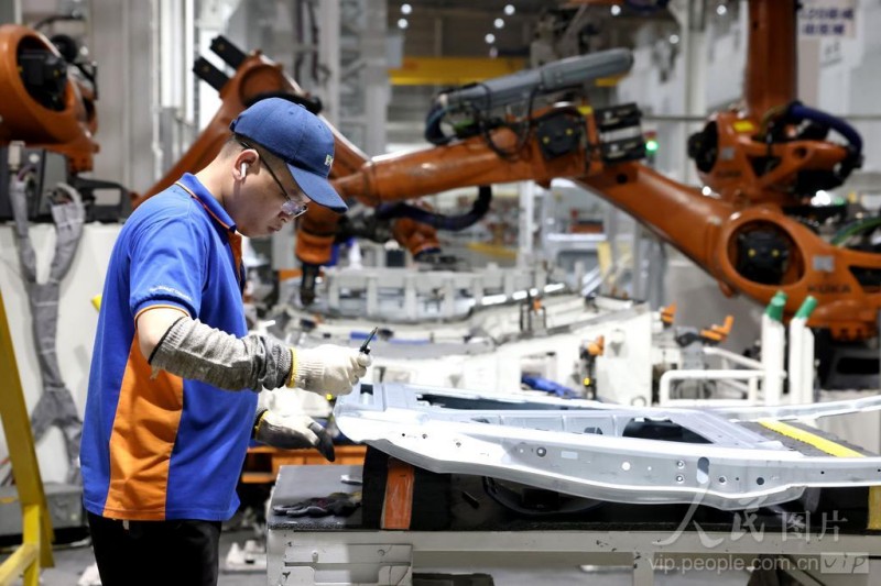 4月16日，在福州荻原泰山友模具冲压有限公司生产车间内，工人配合机器人在生产汽车车身钣金件产品。