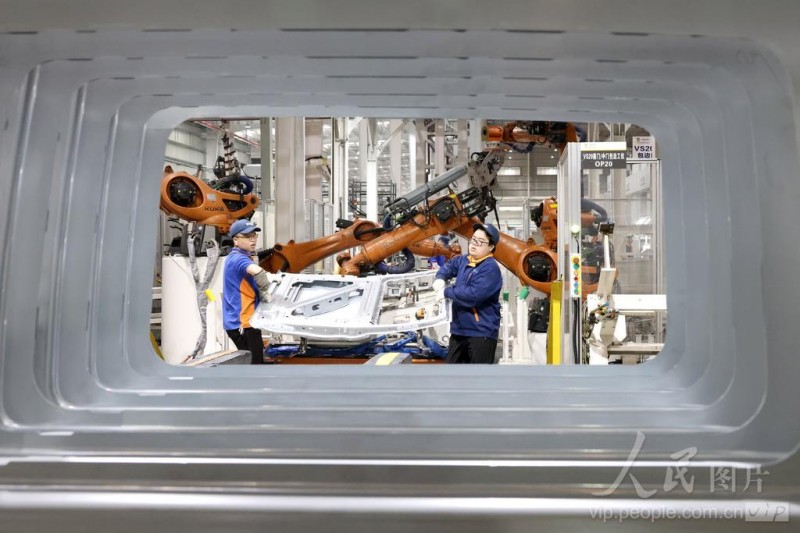 4月16日，在福州荻原泰山友模具冲压有限公司生产车间内，工人配合机器人在生产汽车车身钣金件产品。