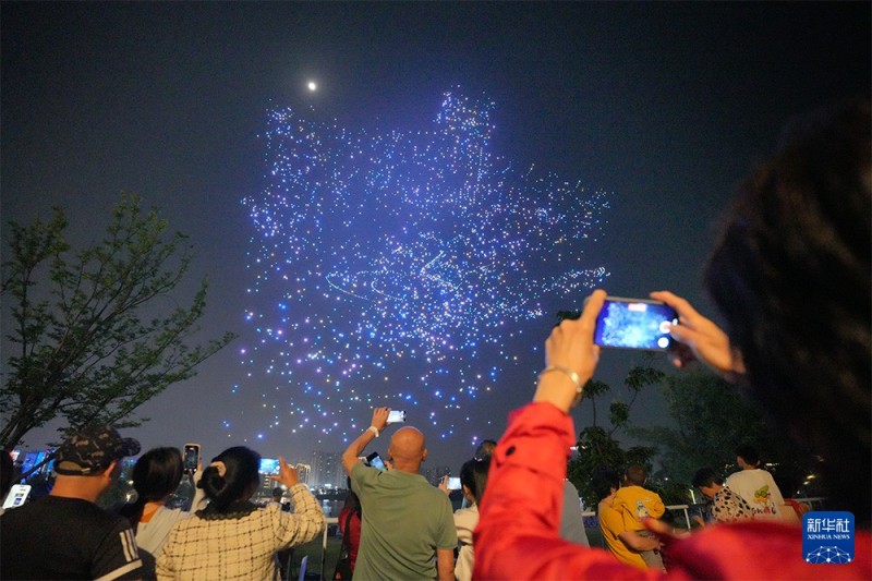 4月28日晚，游客在福州闽侯旗山湖公园拍摄“福聚榕城·数字领航”主题无人机集群光影秀。新华社记者 高咏薇 摄