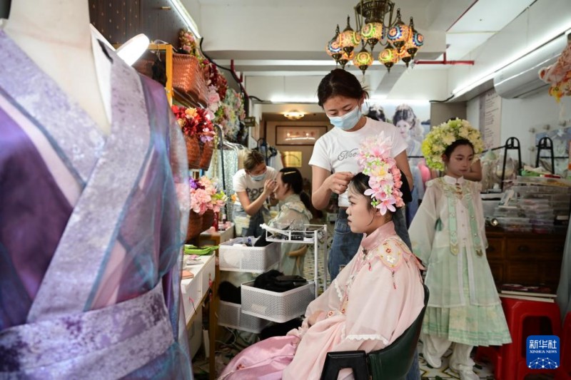 5月2日，福州上下杭历史文化街区的一家簪花妆造店的工作人员为游客制作头饰。新华社记者 林善传 摄