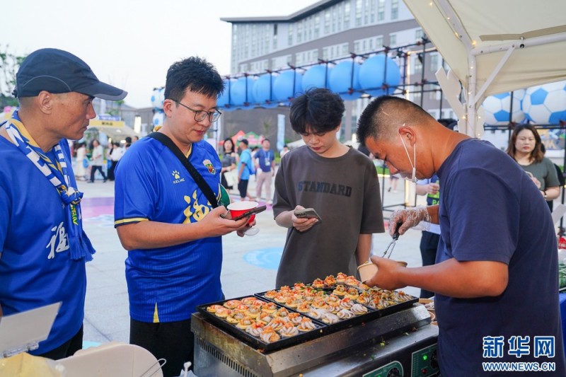 球迷在市集上购买美食。新华网 肖和勇 摄