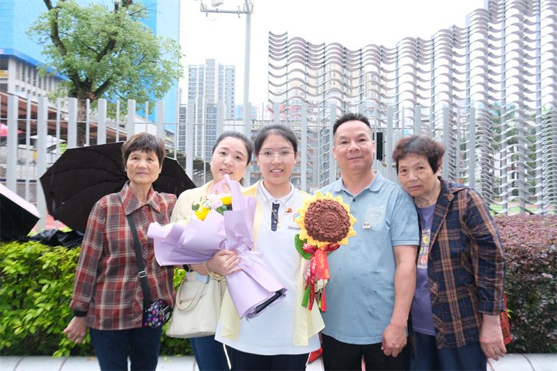 6月9日，福州教育附中考点外，一家人手捧鲜花礼物在考点前合影。