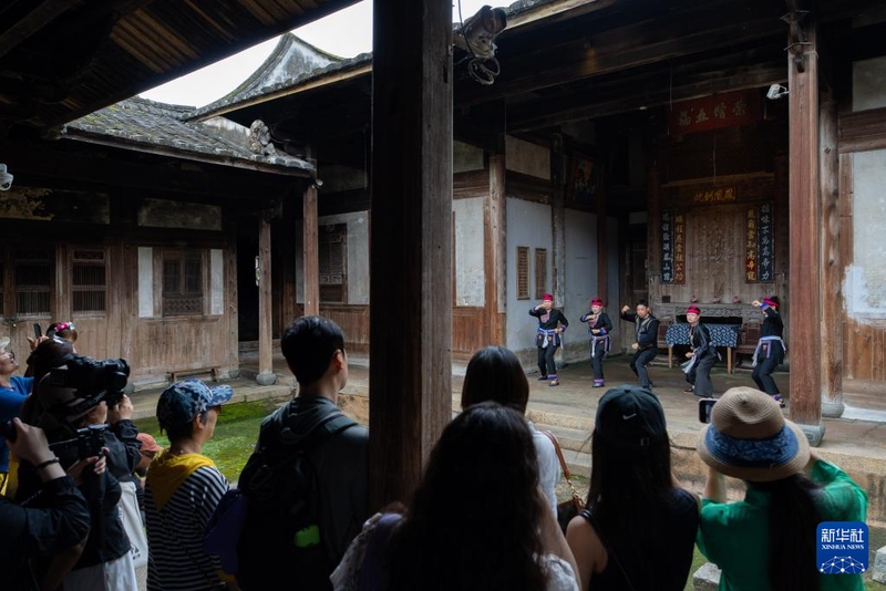 6月10日，游客在半月里村观看畲族武术表演。新华社记者 张笑宇 摄