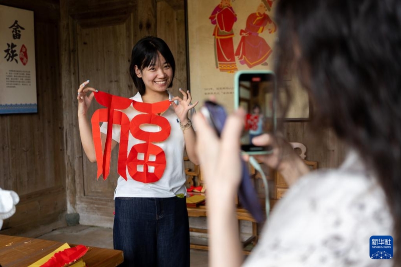 6月10日，一名播客博主在半月里村展示畲族手剪工艺成品。新华社记者 张笑宇 摄