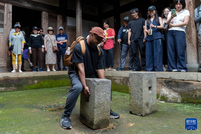 6月10日，一名来自印度尼西亚的播客博主在半月里村尝试搬起重约260斤的传统畲族武术练武石。新华社记者 张笑宇 摄