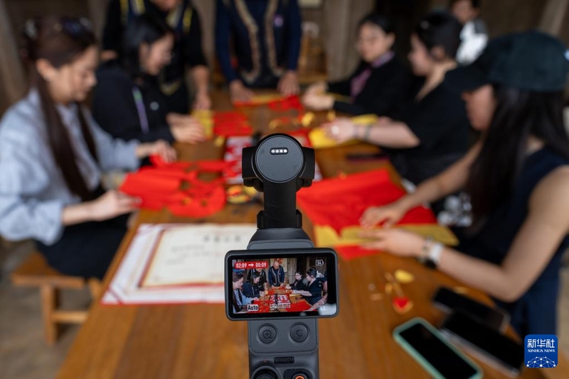 6月10日，几名播客博主在半月里村录制体验市级非物质文化遗产畲族手剪的视频。新华社记者 张笑宇 摄