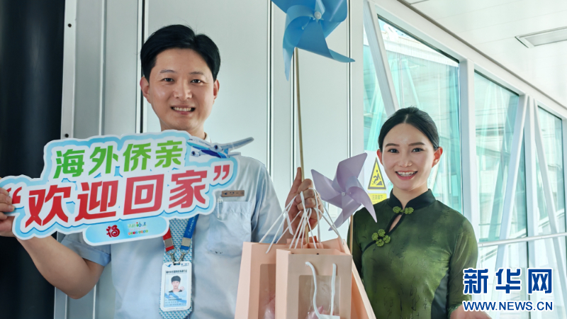 工作人员为首航航班抵达旅客送上小礼物。新华网 刘丰 摄