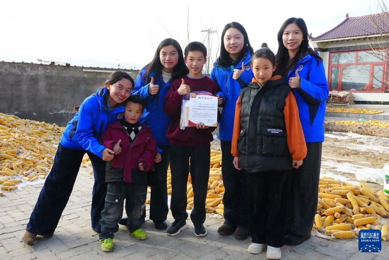 2025年12月14日，支教队员在宁夏中卫市海原县家访，为学生送上“进步报喜单”。新华社发