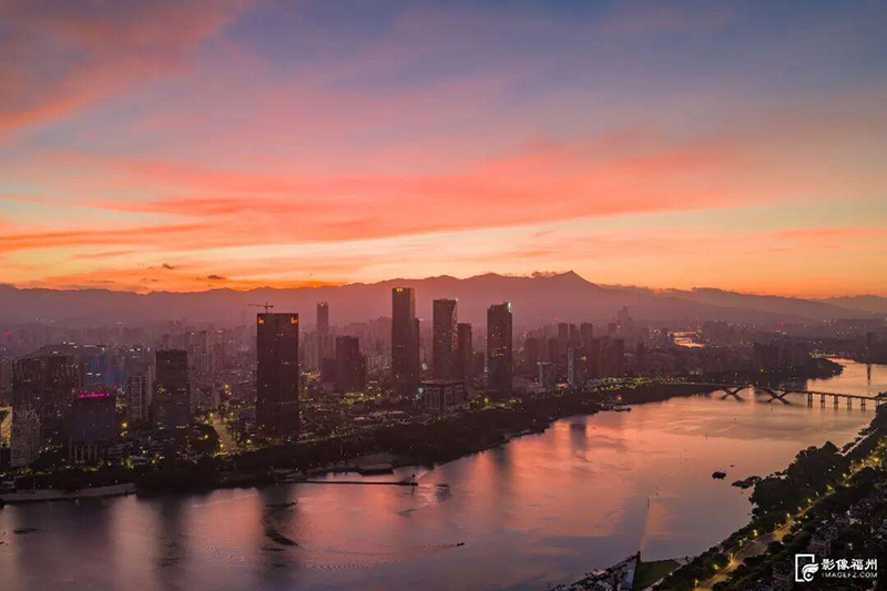 朝霞宛如打翻的调色盘，为城市披上璀璨“金衣”。
