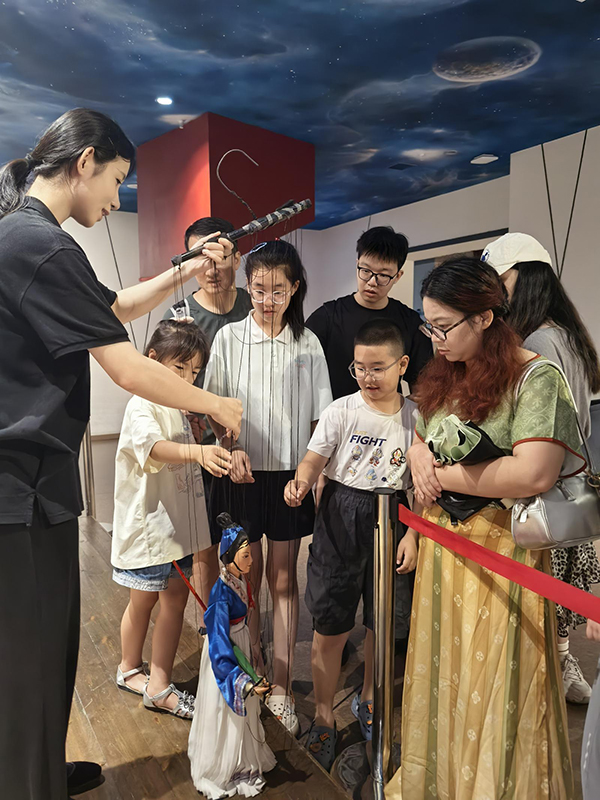 7月15日，泉州市非遗馆，家长带着放假的孩子与提线木偶零距离互动。张九强 摄