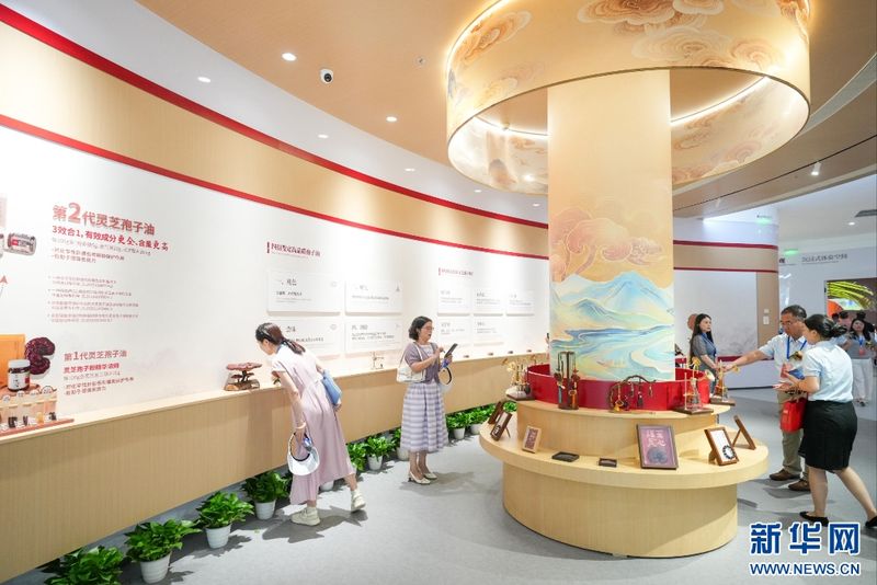 7月24日,嘉宾在展馆了解灵芝产品开发情况。新华网 肖和勇 摄
