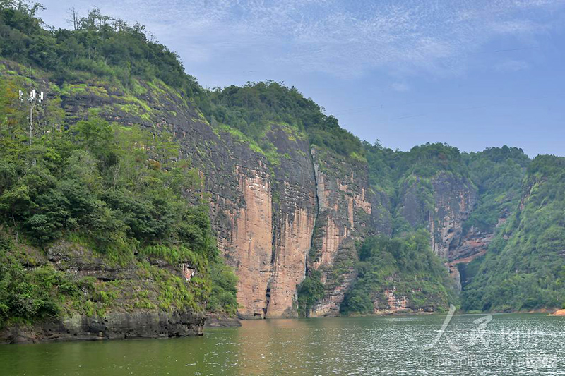 福建泰宁大金湖，巨大丹霞岩壁临水矗立，岩层纹理清晰，展现壮美的水上丹霞地貌。