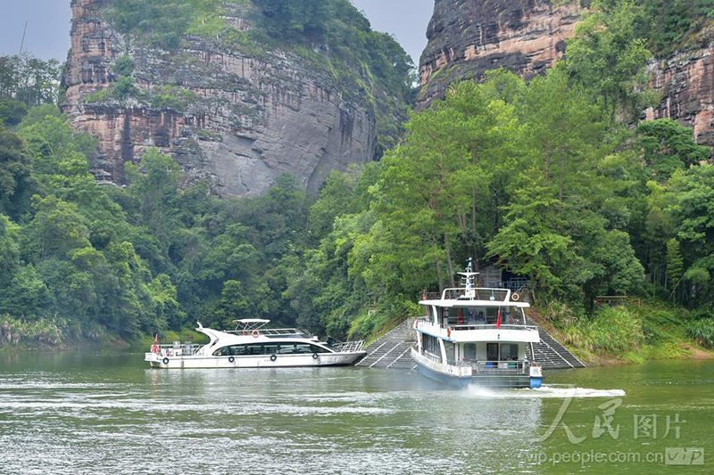 泰宁大金湖景区，两艘游船停靠湖畔码头，巍峨丹霞岩壁与葱郁林木相映成趣。
