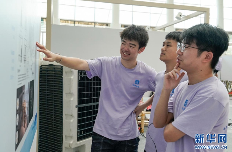 来自湖南大学的青年学子在作品搭建的间隙讨论设计图纸。新华网 蒋巧玲 摄