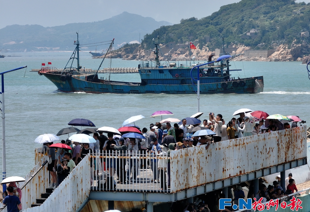 岸边，老少咸集、观者如潮，用手机、相机记录这一开渔盛况。