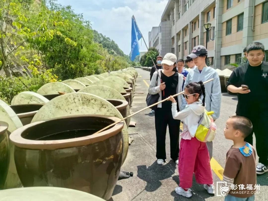游客在酱油露天晾晒场体验酱油搅缸。民天食品供图
