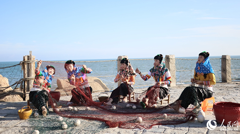 身着特色传统服饰的惠安女模特队，在海边修补渔网。人民网记者 李昌乾 摄
