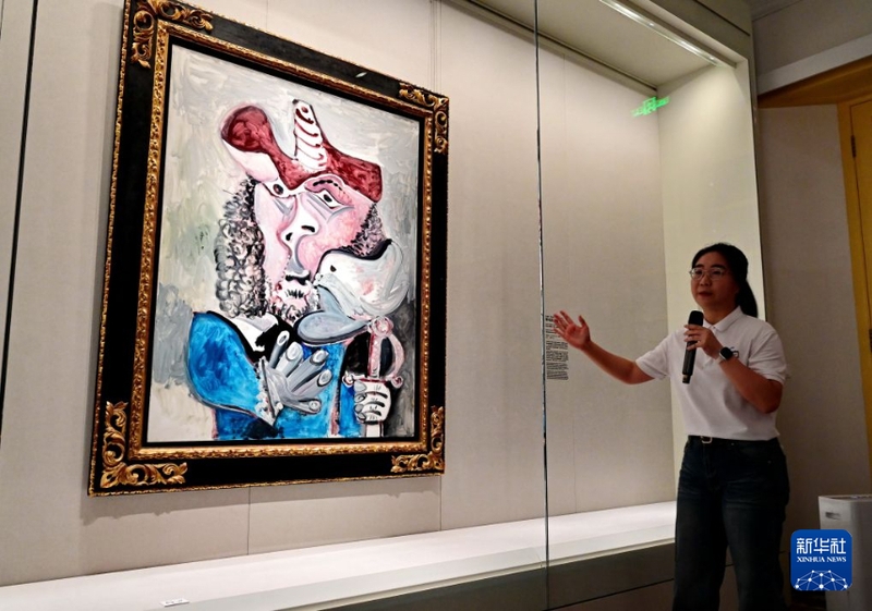 8月22日，中国美术馆鼓浪屿艺术空间工作人员为游客介绍在该馆展出的巴勃罗·毕加索的绘画作品《带鸟的步兵》。新华社记者 林善传 摄