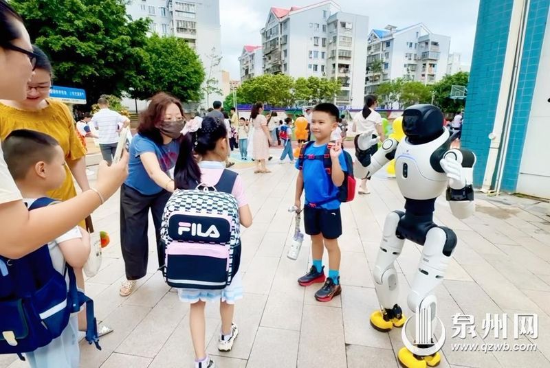 8月31日，丰泽区第二实验小学举行新生见面会，学校老师们与机器人在校门口迎接孩子们入校。