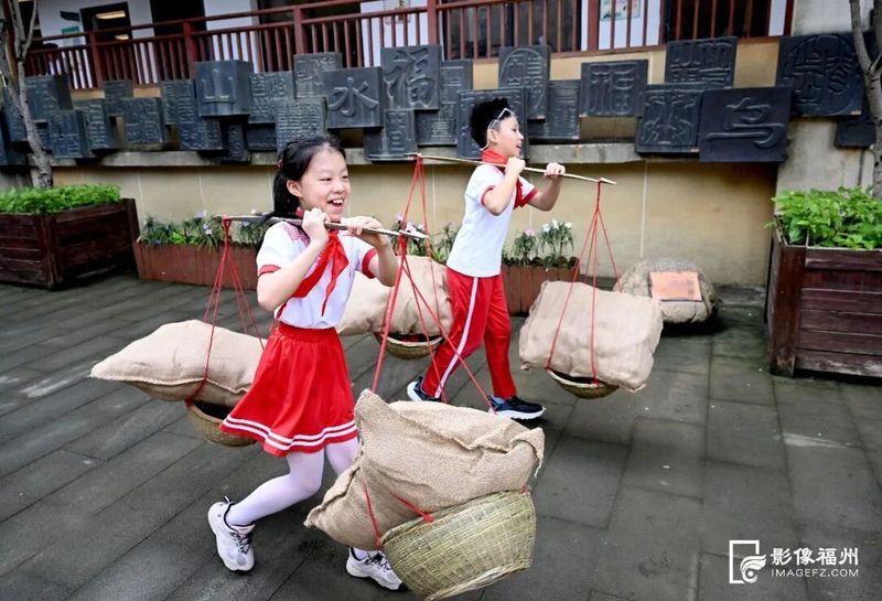 在乌山小学,孩子们肩挑扁担感受当年支前队伍翻山送粮的艰辛。记者 石美祥 摄