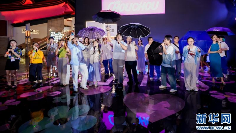 8月28日举行的阿卡贝拉快闪活动现场下起了小雨，一众音乐爱好者撑起雨伞，在湿漉漉的户外舞台上共同欢唱。地面倒映着斑斓灯光，歌声冲破雨夜，尽显人声合唱的热烈氛围。新华网发（主办方供图）