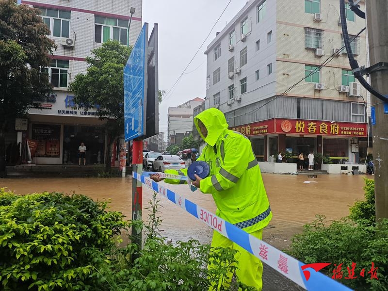 1日，仙游县公安局民警在当地积水路段拉起警戒线，做好现场隔离警示，提醒群众远离危险积水区域。陈婧 摄