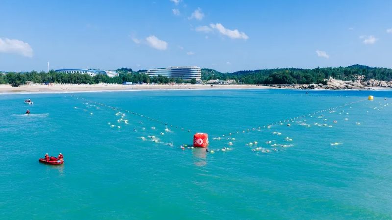 选手们纵身跃入浪涛翻涌的海域，劈波斩浪完成750米游泳。