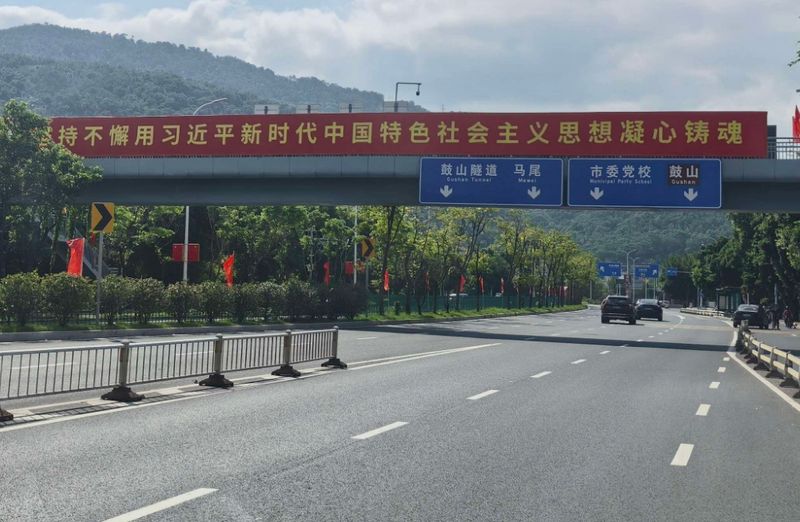 人行天桥化作空中红色长廊，护栏两侧整齐排列的五星红旗，像迎风挺立的红色卫士，红旗随风摇曳，与远处城市楼宇相映生辉，满眼尽是喜庆红韵。