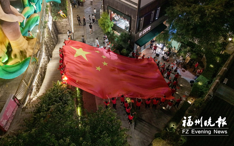 在烟台山，人们伸手托举起一面大大的国旗。