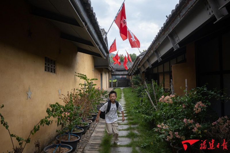 9月29日，中复村一个男孩跑过插满红军旗帜的陈列馆。