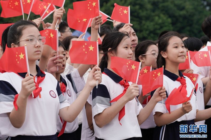 学生们挥舞国旗，等待福州舰靠岸。新华网 蒋巧玲 摄