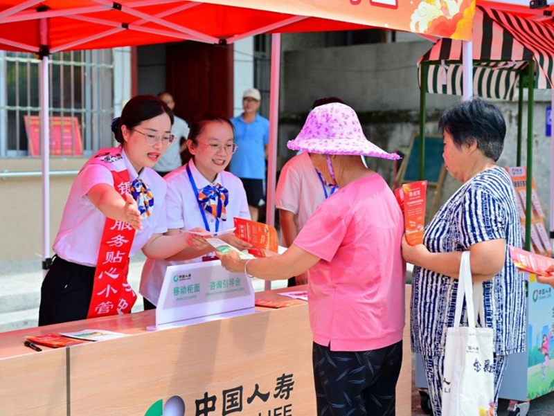 2025年8月1日，中国人寿福建省分公司“红土拥军鱼水情 金融敬老暖银龄”主题活动现场，工作人员为老年群众提供现场咨询与便民服务。2025年，“银龄安康 金融敬老”项目已实现龙岩市辖内每个县区至少结对帮扶一家长者食堂，为13万名老年人提供意外保险保障，保障金额超20亿元，智慧体检及医疗权益受益3万人次。新华网发（陈唐烨 摄）
