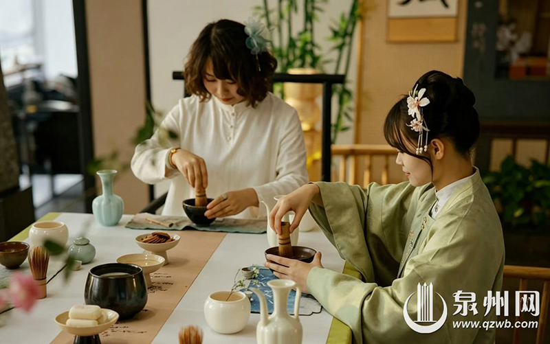 茶馆主理人和身穿汉服的游客一起点茶